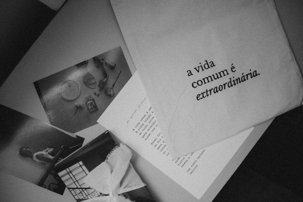 Monochrome still life featuring Portuguese text 'a vida comum é extraordinária' on paper.