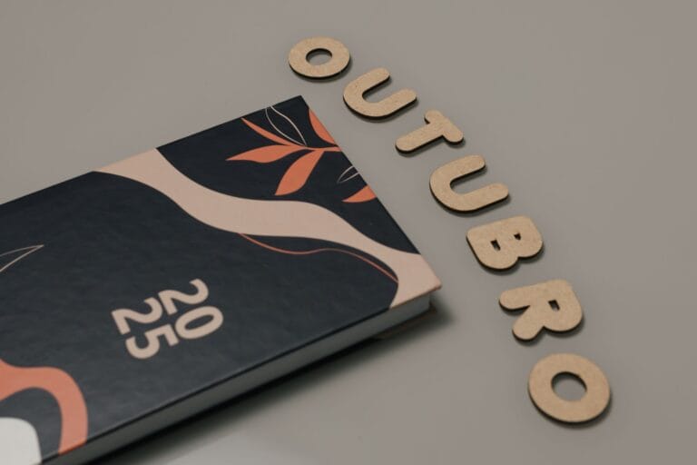 Minimalist flat lay featuring a 2025 planner and cut-out letters spelling 'OUTUBRO'.