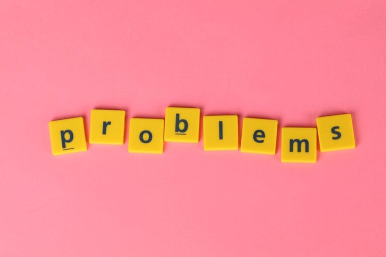 Yellow letter tiles spelling 'problems' on a contrasting pink background. Perfect for creative design projects.