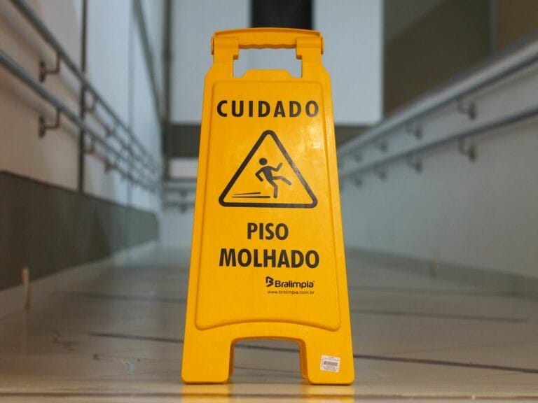 Bright yellow caution sign signals wet floor in a corridor with tiled flooring.