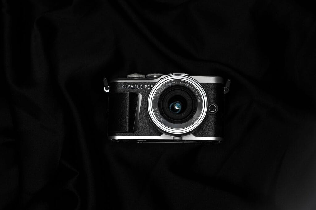 Stylish Olympus Pen camera with lens, placed on a dark, moody background.