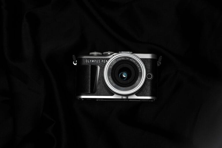 Stylish Olympus Pen camera with lens, placed on a dark, moody background.