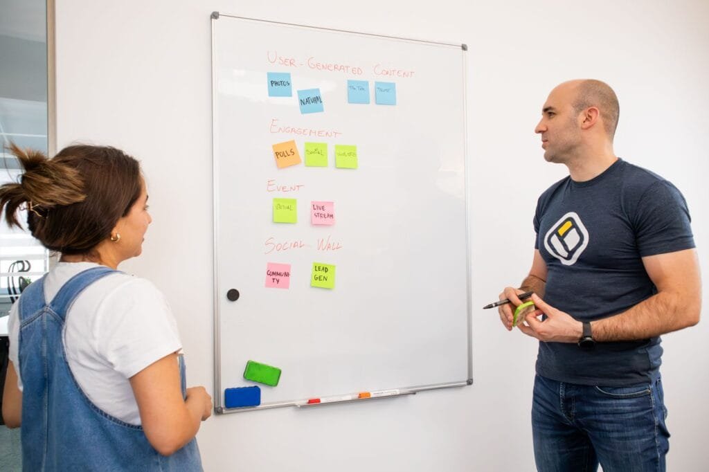 Colleagues brainstorm on project strategy using whiteboard notes at the office.