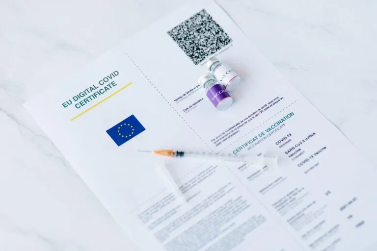 EU digital COVID certificate with vaccine vials and syringe on a white background.