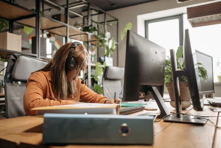 Focused woman with headset working in a modern office environment.